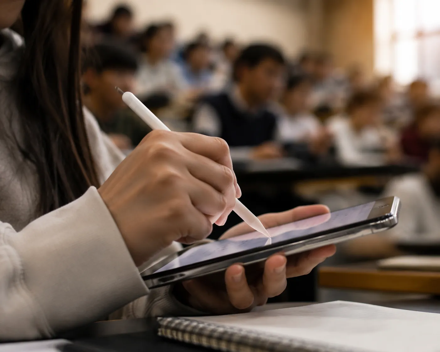 Student writing on a smartphone with a stylus in a lecture hall