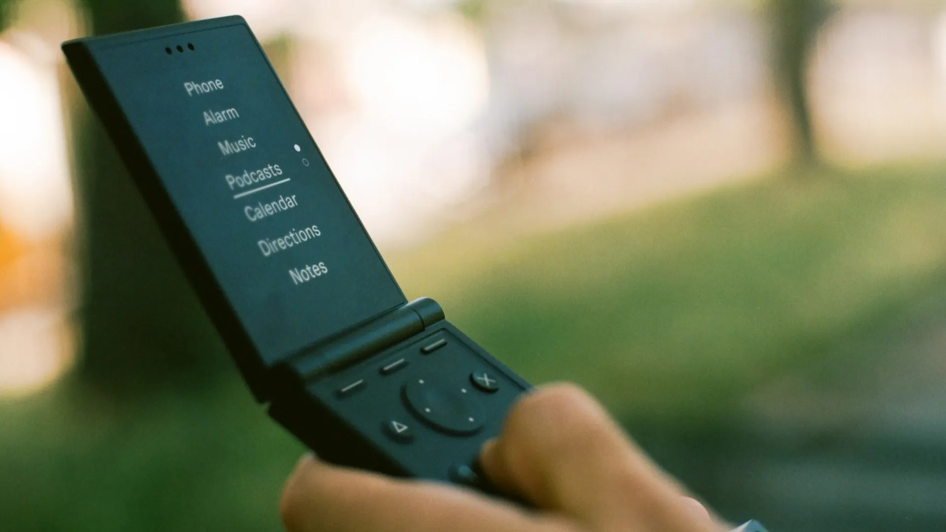 The Light Flip phone held open showing its matte OLED screen, T9 keypad, D-pad navigation, and clamshell form